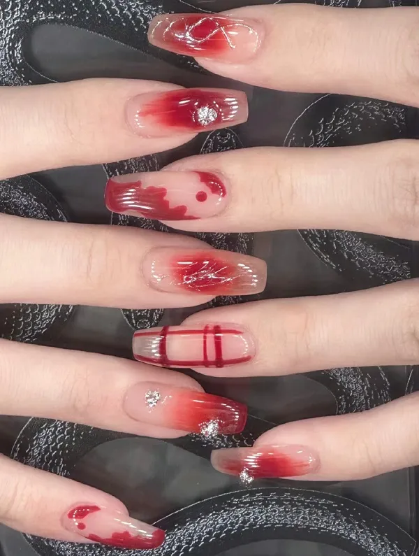 Nail cô dâu màu thạch móng tay cắt tỉa với thiết kế đỏ và trắng trên chúng ngồi bề mặt đen