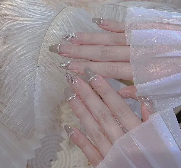 Nail cô dâu sang chảnh đôi tay của phụ nữ với móng trắng và bạc trên một chiếc váy