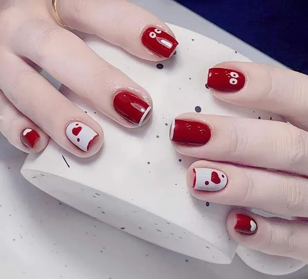 Nail cute có một người phụ nữ móng tay màu đỏ và trắng cầm tách cà phê
