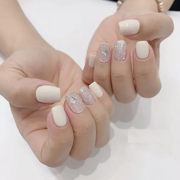 Nail màu trắng gạo đây là hình ảnh bàn tay của một người phụ nữ với móng và bạc