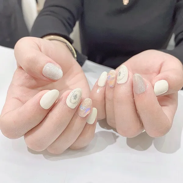 Mẫu nail trắng có hai bàn tay với sơn móng và bạc trên chúng