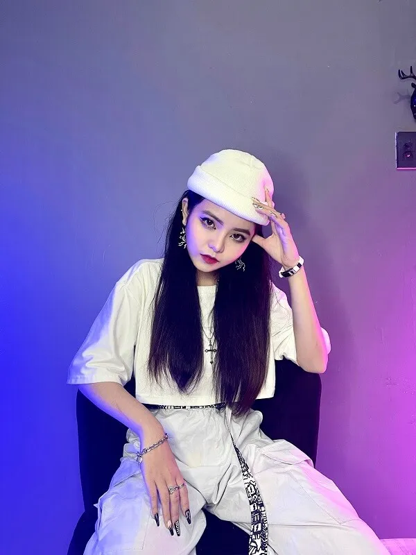 Reency ngô người phụ nữ trẻ ngồi trên ghế mặc trang phục màu trắng và mũ