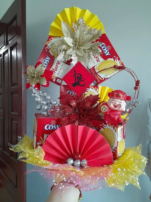 Có một người cầm cây thông noel làm bằng giấy đỏ và vàng