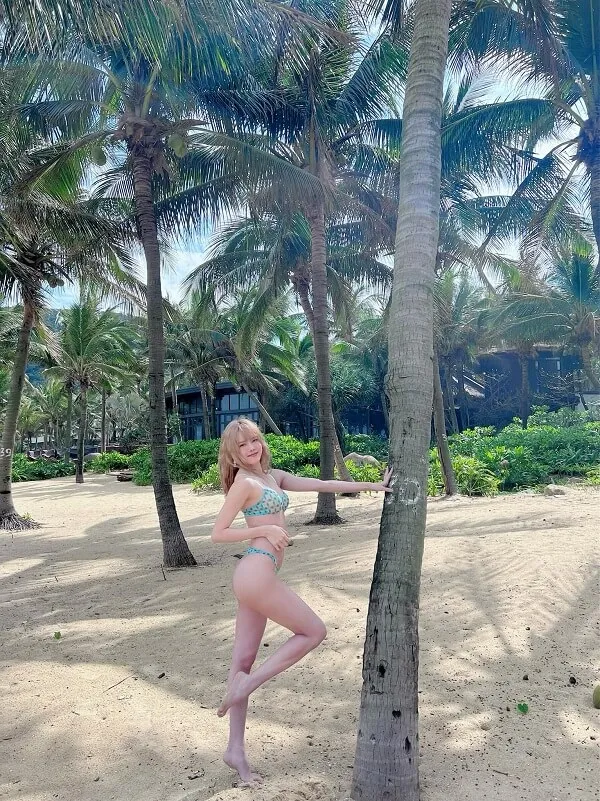 Thiều bảo trâm bikini có một người phụ nữ mặc đứng cạnh cây cọ