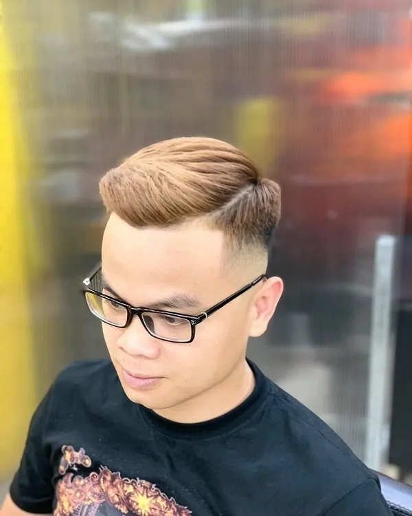 Tóc mohican có một chàng trai trẻ với kính nhìn vào điện thoại di động của mình