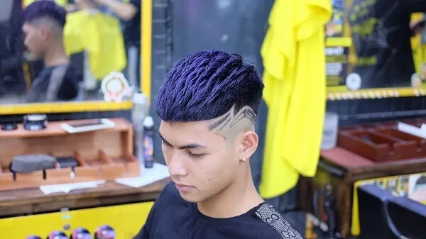 Tóc mohican có một chàng trai trẻ với mái màu tím trong cửa hàng cắt