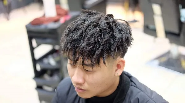 Tóc mohican có một chàng trai trẻ ngồi trong cửa hàng cắt với kiểu của mình