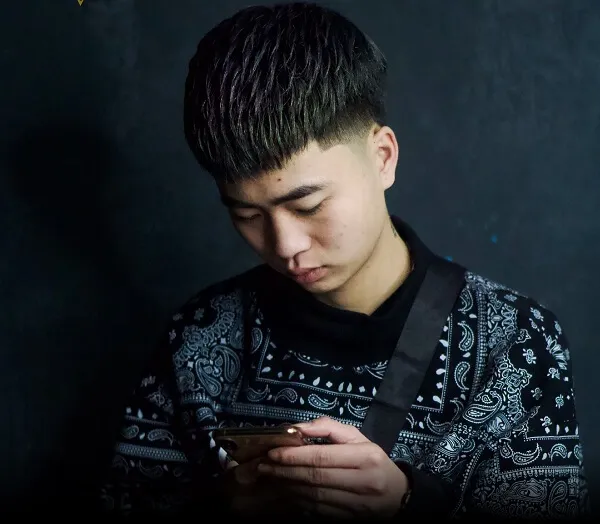 Tóc mohican ngắn có một chàng trai trẻ đang nhìn vào điện thoại di động của mình