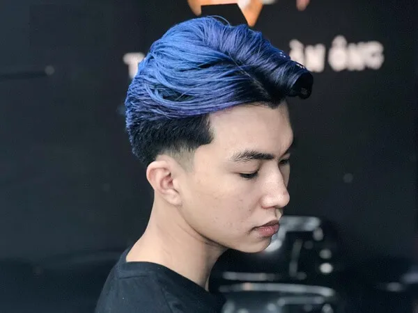 Tóc nam side part ngắn có một chàng trai trẻ với mái nhuộm màu xanh trong cửa hàng cắt