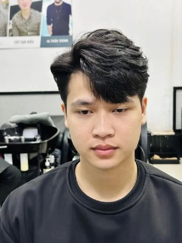 Tóc nam side part ngắn có một chàng trai trẻ đang ngồi trong tiệm làm