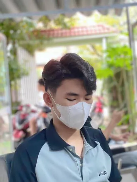 Tóc nam side part có một người đàn ông đeo mặt nạ trong khi nhìn vào điện thoại di động của anh ấy