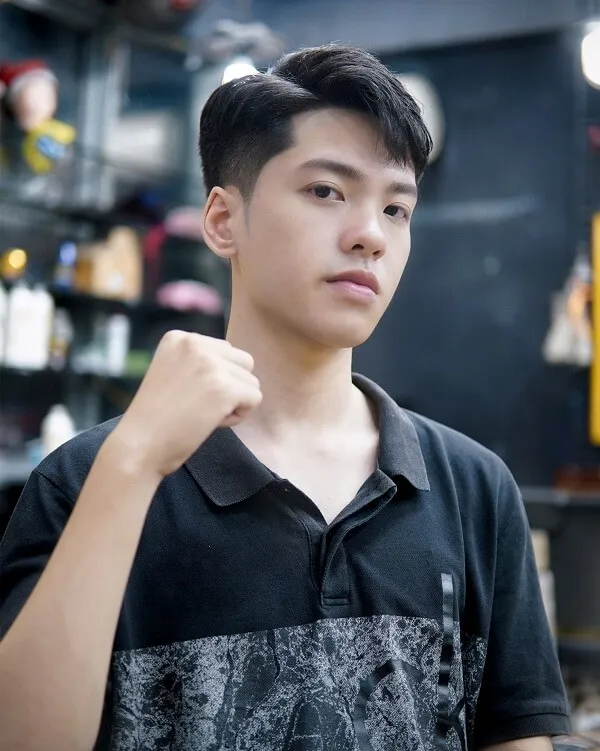 Tóc nam có một chàng trai trẻ đang đứng trong cửa hàng cắt với nắm đấm của mình