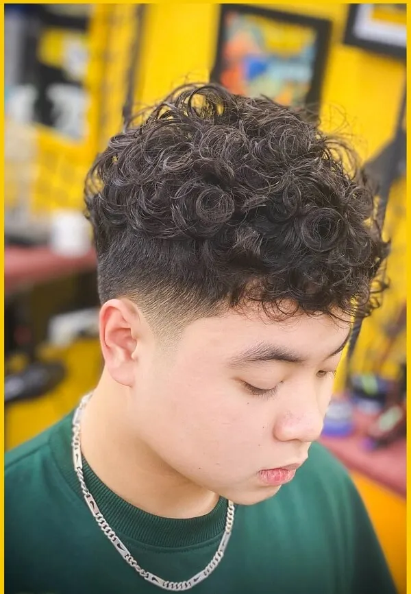 Tóc nam undercut đây là hình ảnh của một chàng trai trẻ với mái xoăn trong cửa hàng cắt