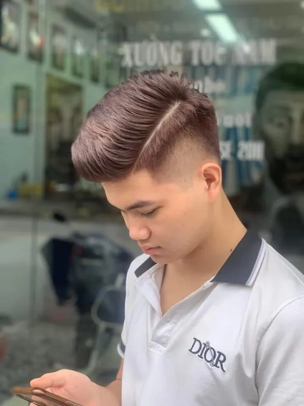Kiểu tóc nam undercut ngắn có một chàng trai trẻ đang nhìn vào điện thoại di động của mình
