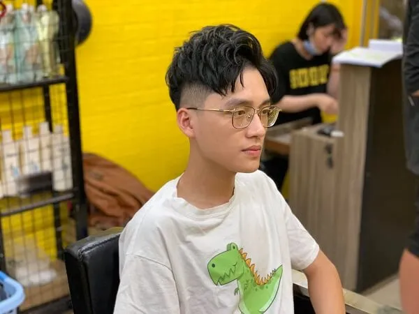 Tóc nam side part dài có một chàng trai trẻ ngồi bàn làm việc trước máy tính