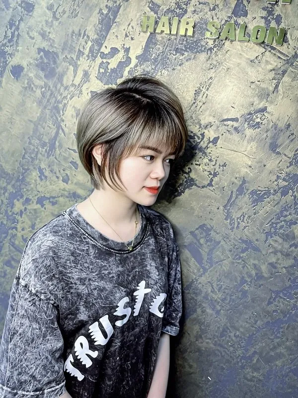 Tóc tomboy có một phụ nữ trẻ đứng trước bức tường mặc áo phông