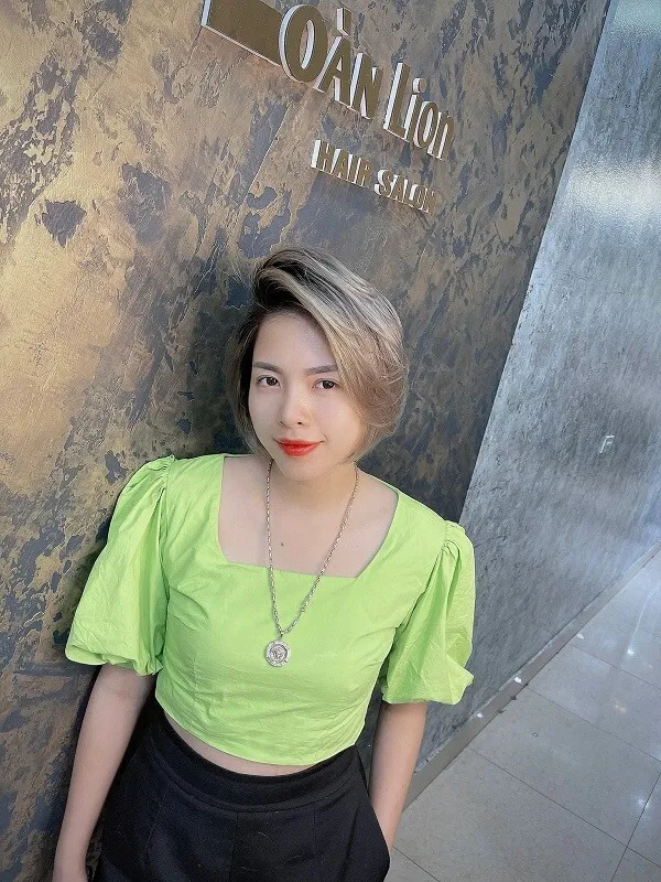 Tóc tomboy cho nữ có một người phụ đứng trước bức tường đeo đầu màu xanh lá cây