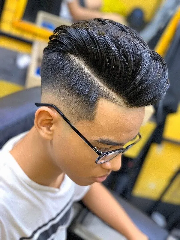Tóc nam undercut có một chàng trai trẻ với kính ngồi trong cửa hàng cắt