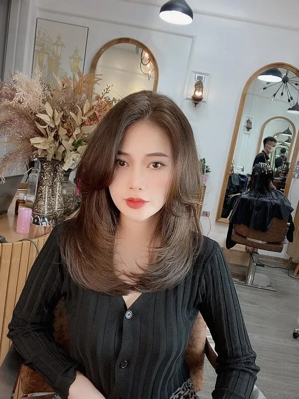 Tóc uốn chữ tầng có một người phụ nữ đang ngồi trên ghế trong tiệm