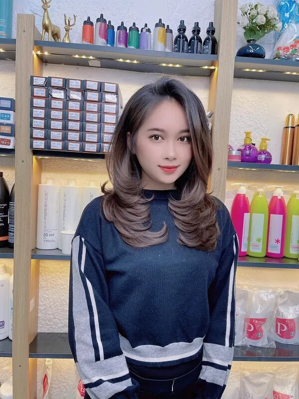 Tóc ngang lưng uốn đuôi chữ có một người phụ nữ đang đứng trước kệ của các sản phẩm