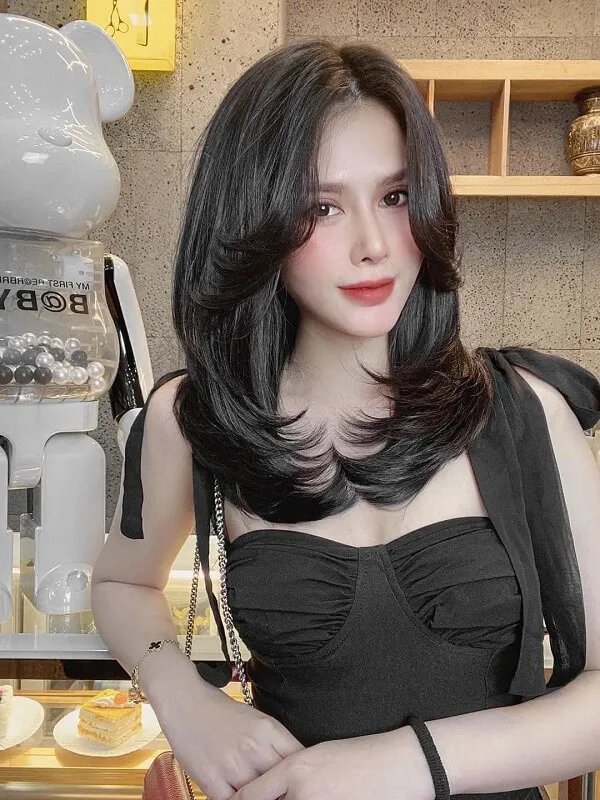 Tóc uốn chữ có một người phụ nữ mặc chiếc váy đen đứng trước robot