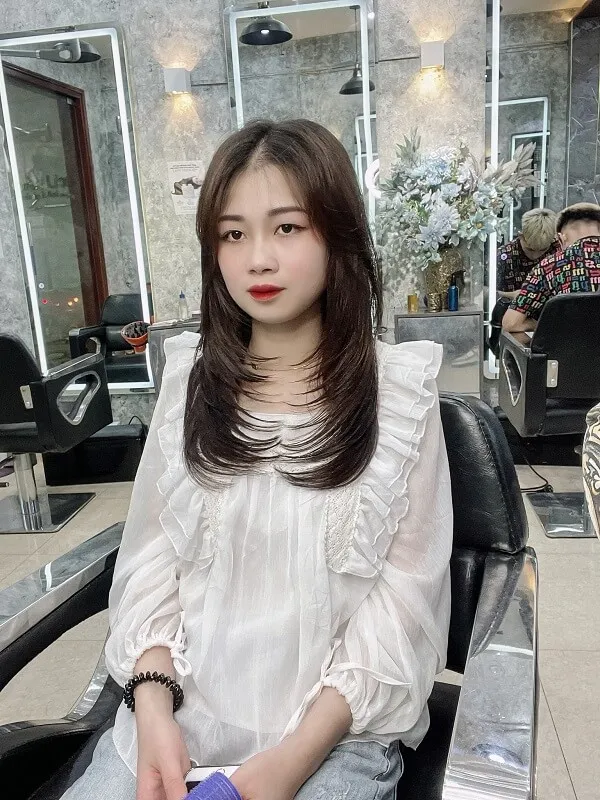 Tóc uốn chữ tầng có một người phụ nữ đang ngồi trên ghế với điện thoại di động
