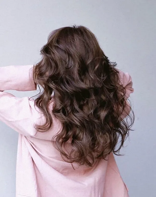 Tóc xoăn sóng có một người phụ nữ mái nâu dài mặc áo sơ mi màu hồng
