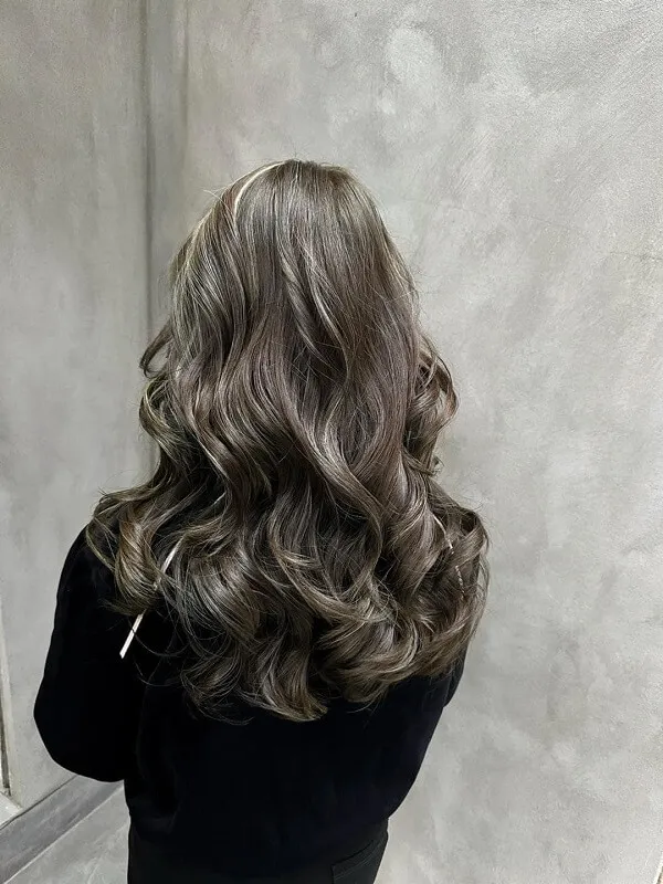 Tóc xoăn sóng người phụ nữ vàng với mái dài gợn đứng trước gương