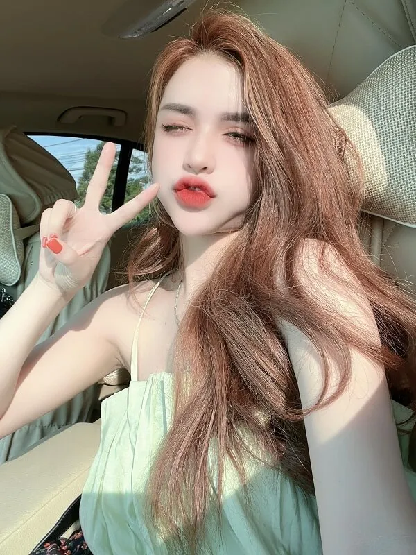 Tóc xoăn sóng lơi ngang vai có một người phụ nữ đang ngồi trong chiếc tô làm dấu hiệu hòa bình