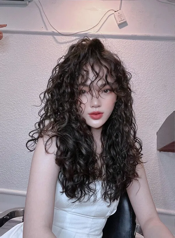Tóc xoăn sóng lơi ngang lưng có một người phụ nữ mái dài ngồi trên ghế