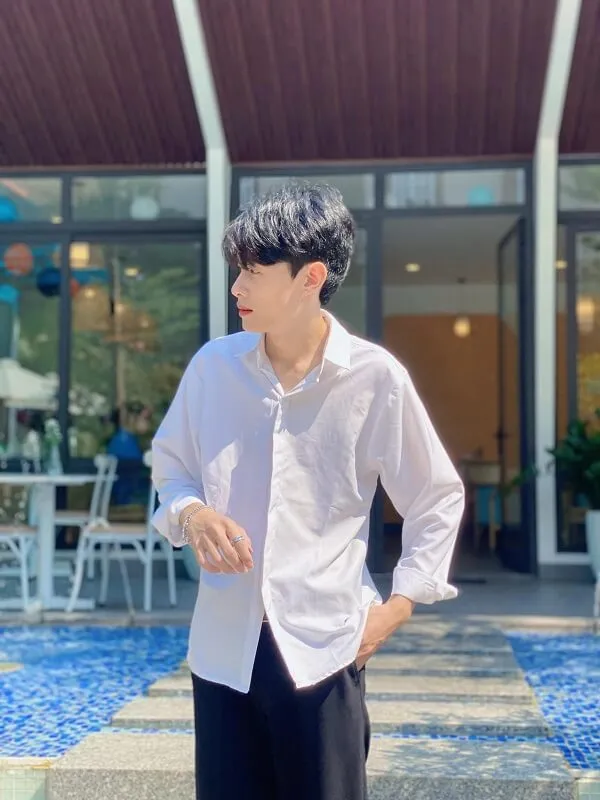 Ảnh trai đẹp 12 tuổi việt nam đây là một người đàn ông đứng trước hồ bơi mặc áo sơ mi trắng và quần đen